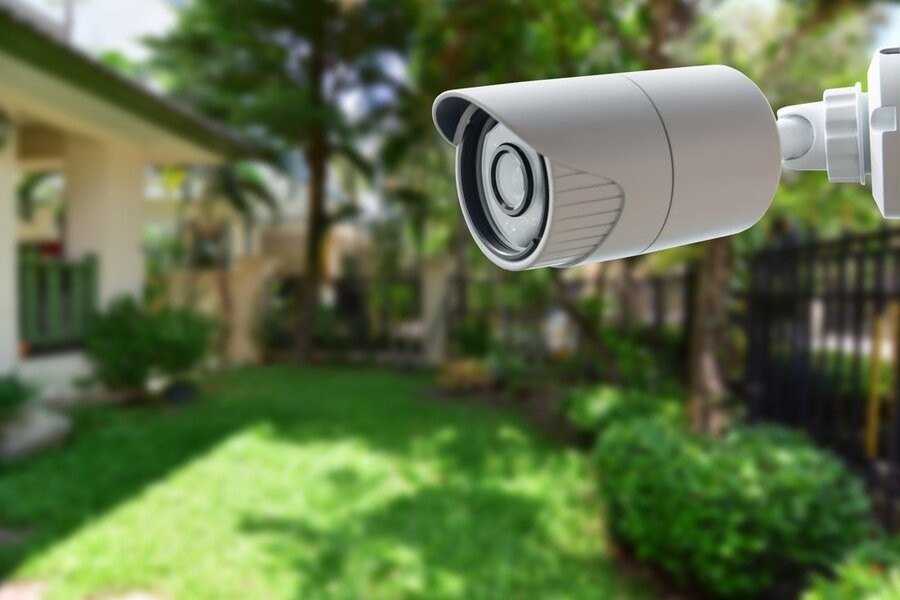 A smart security system’s surveillance camera in focus with a backyard in the background