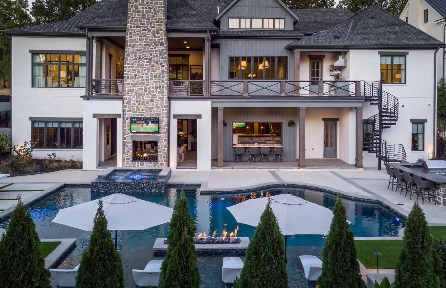 A backyard with a pool, fire pit, outdoor TV, and fireplace.