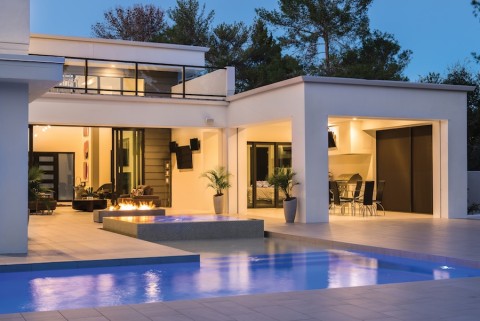 A contemporary backyard with a pool and a patio area with motorized shades rolled up fully.