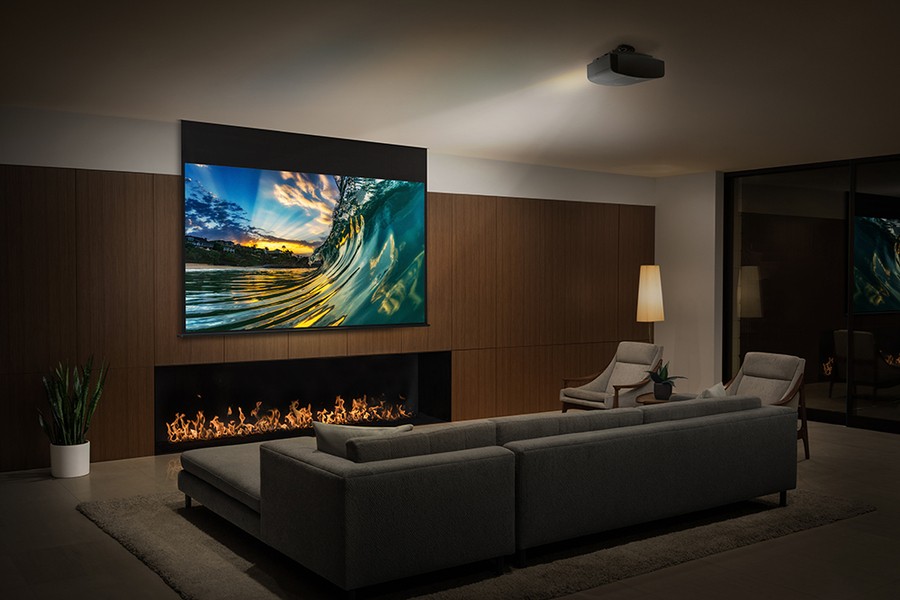 A modern media room features a large projector screen displaying a vibrant ocean wave scene, with comfortable seating including a sectional sofa and armchairs
