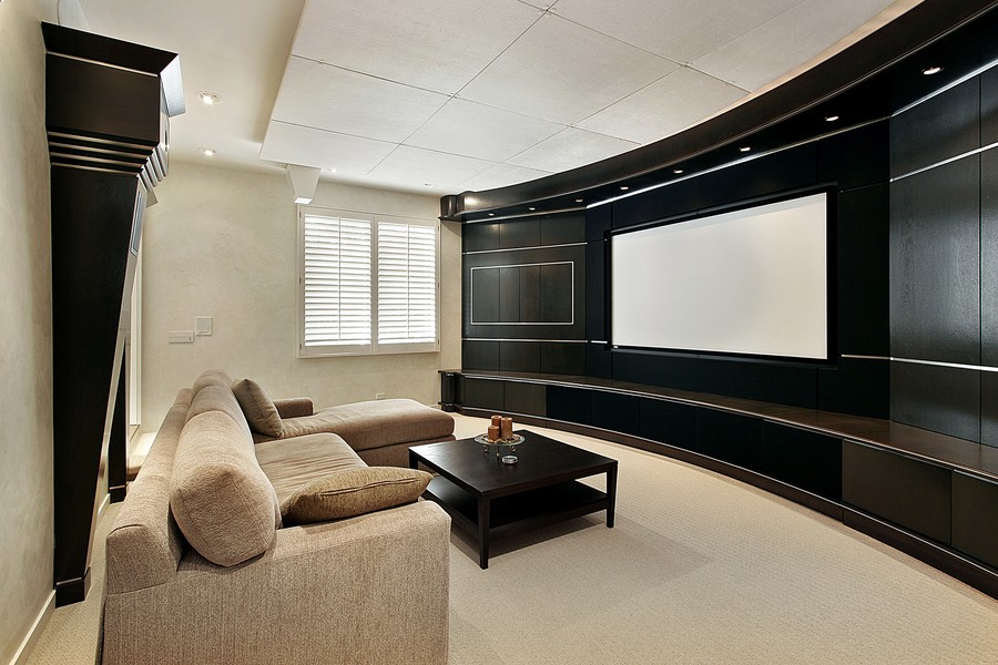  Image is of a beautiful home theater with a black wall color and beige furniture color scheme.