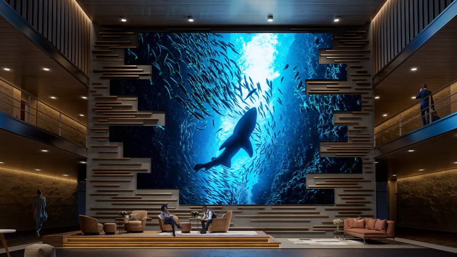 A large video wall in a lobby depicting a shark and small fish swimming.