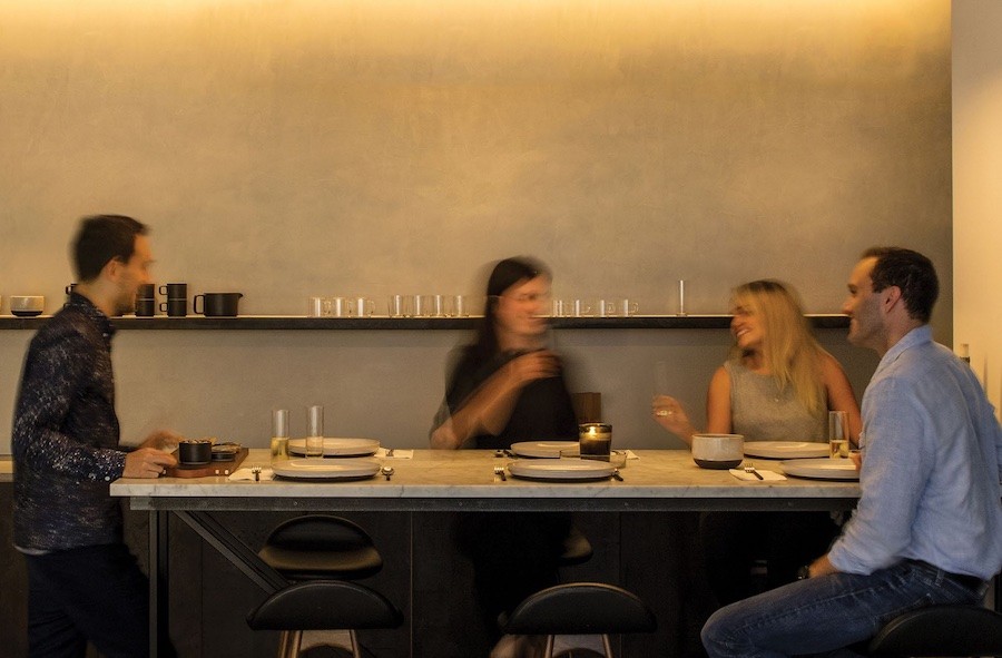 A warmly lit dining area where friends are enjoying a dinner together.