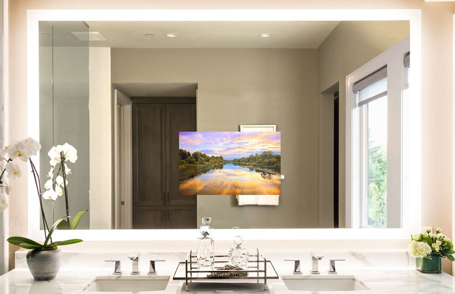 A Séura lighted mirror with a built-in TV in a bathroom above the counter.