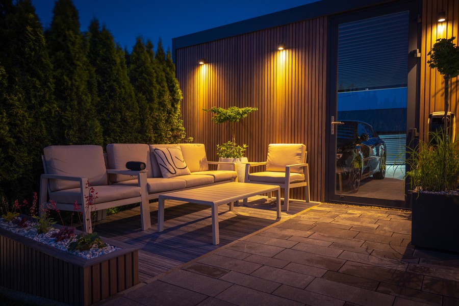 A patio with wooden walls illuminated by outdoor lighting.