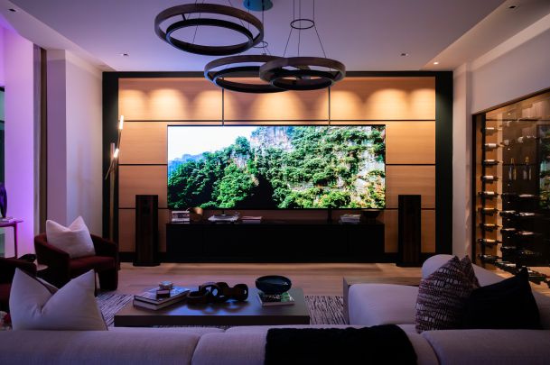 Upscale home theater area with a bright Just Video Walls screen displaying lush green cliffs.