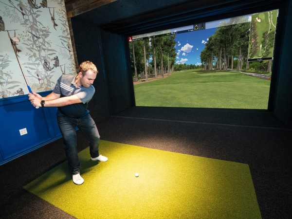 A digital golf simulator view showing a golf course with player metrics and controls.